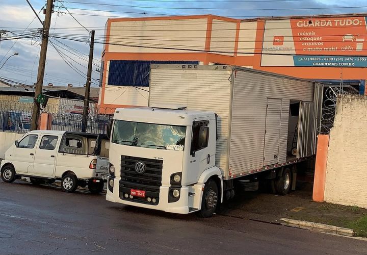 Caminhão estacionado em frente a um galpão de guarda-móveis